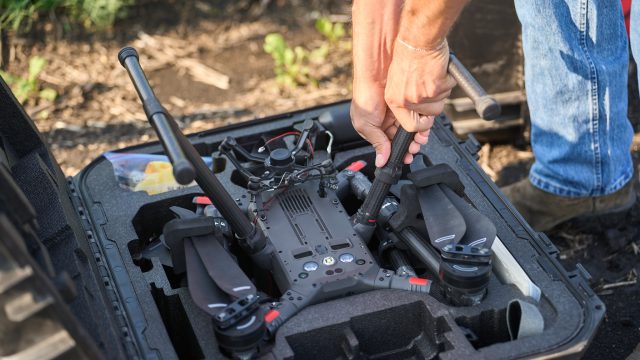 A pair of hands lift a drone out of its case.